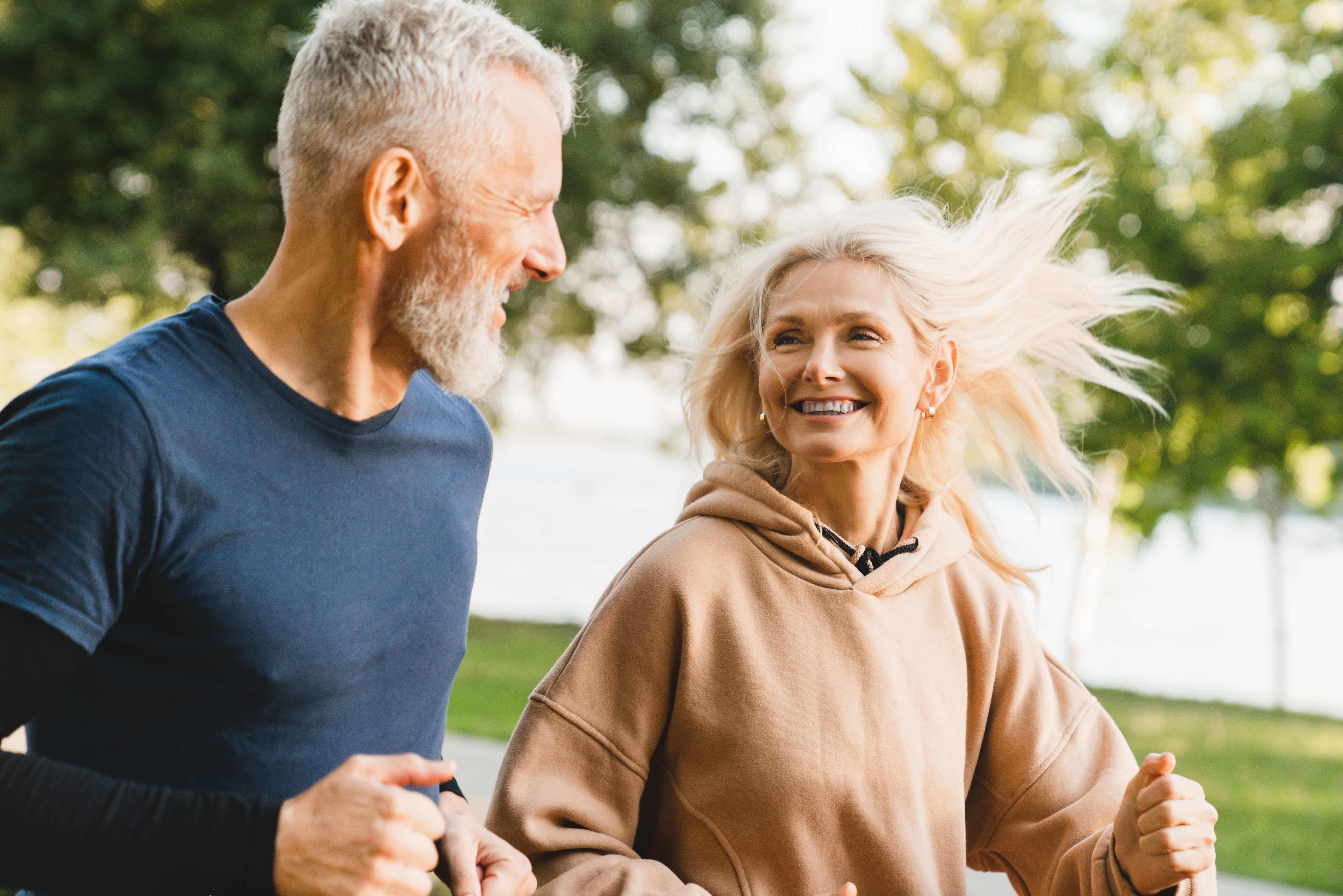 Close-up of older couple smiling at each other as they run outside Close-up of older couple smiling at each other as they run outside